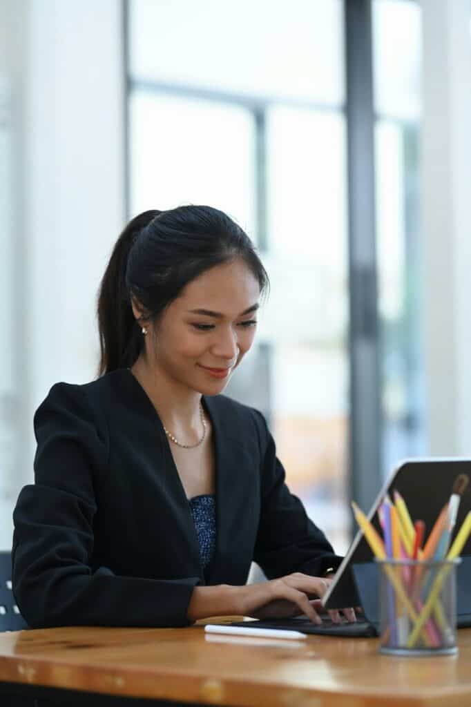 Data entry specialist typing on laptop at wooden desk