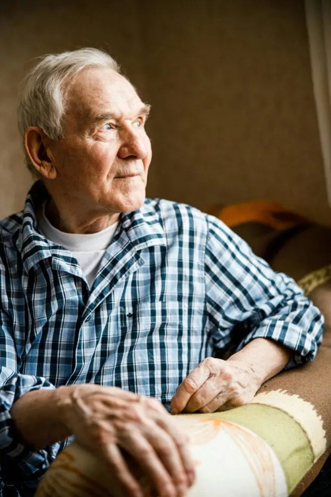 Elderly man receiving gentle dementia care support in comfortable home setting