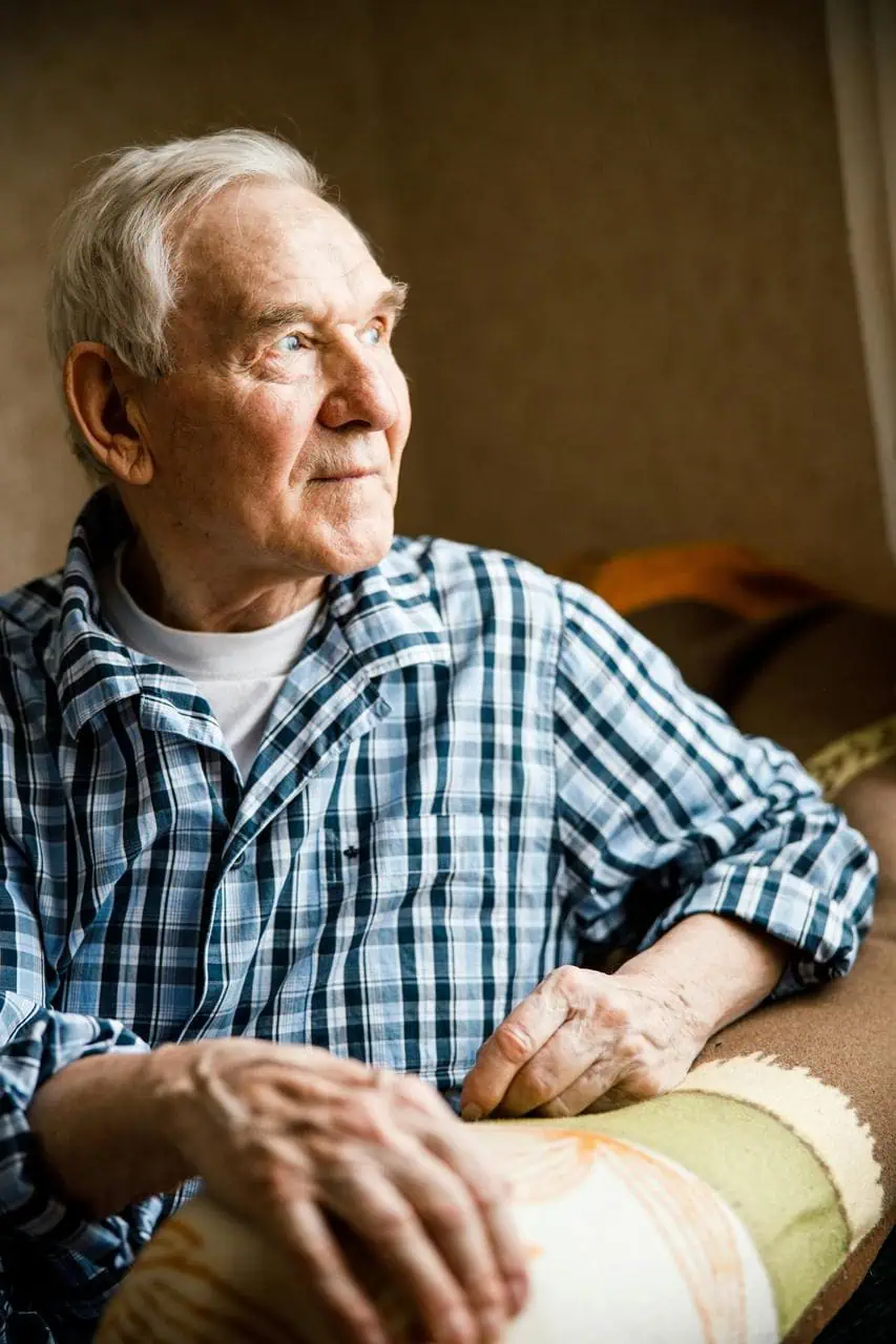 Elderly man receiving gentle dementia care support in comfortable home setting