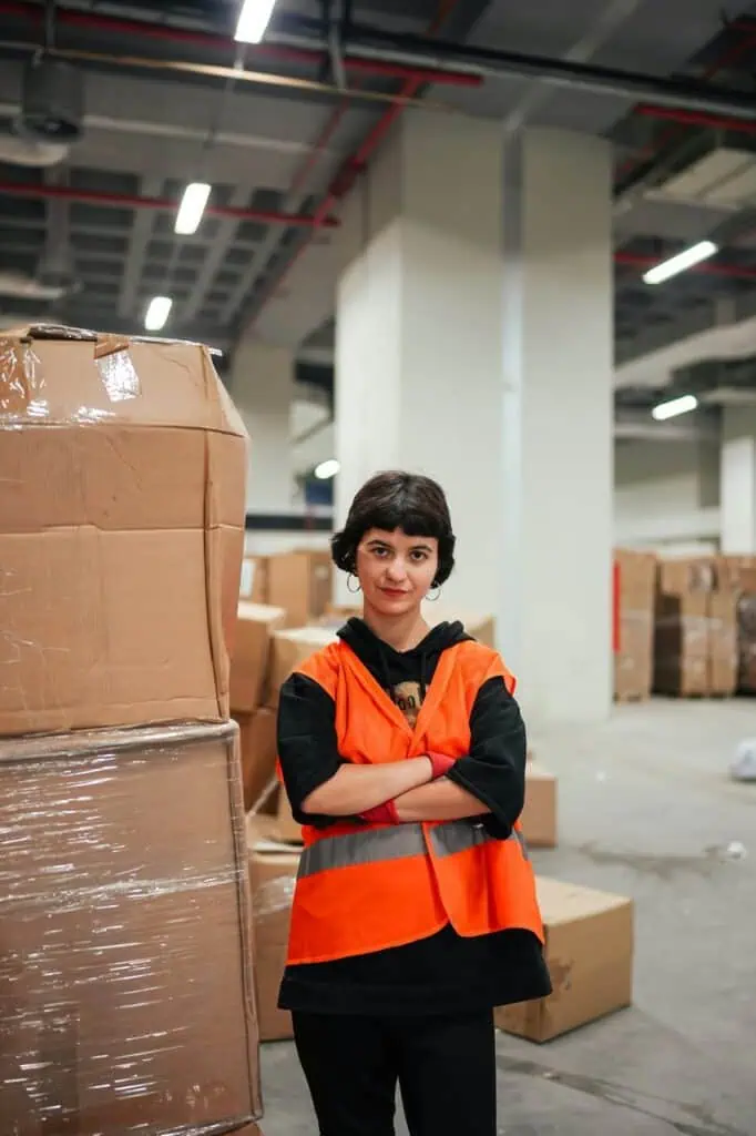 Export and import compliance manager standing in warehouse with shipping boxes