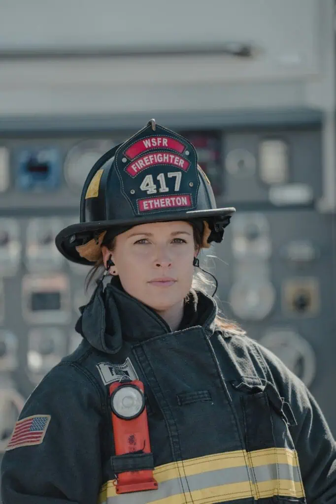 Female firefighter in uniform standing confidently at fire truck control panel