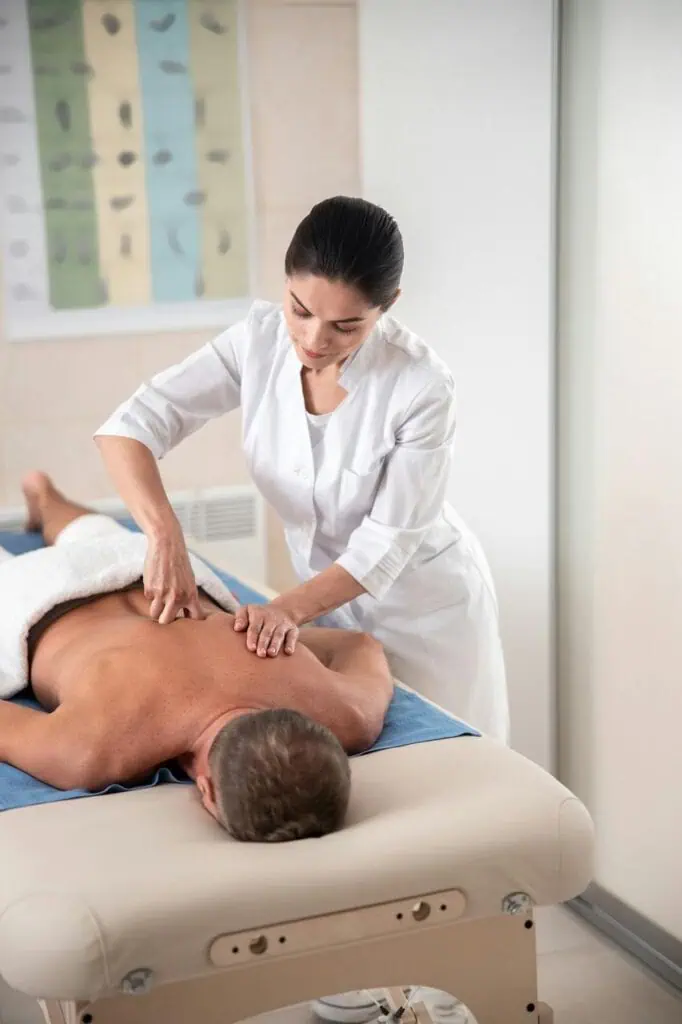 Holistic massage therapist performing therapeutic back massage on client in spa