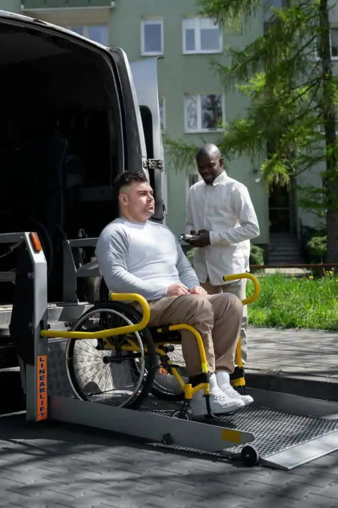 mobility aid specialist assisting patient in wheelchair onto vehicle lift outdoors