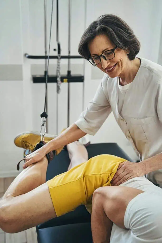 Female physical therapist treating patient leg injury in rehabilitation clinic