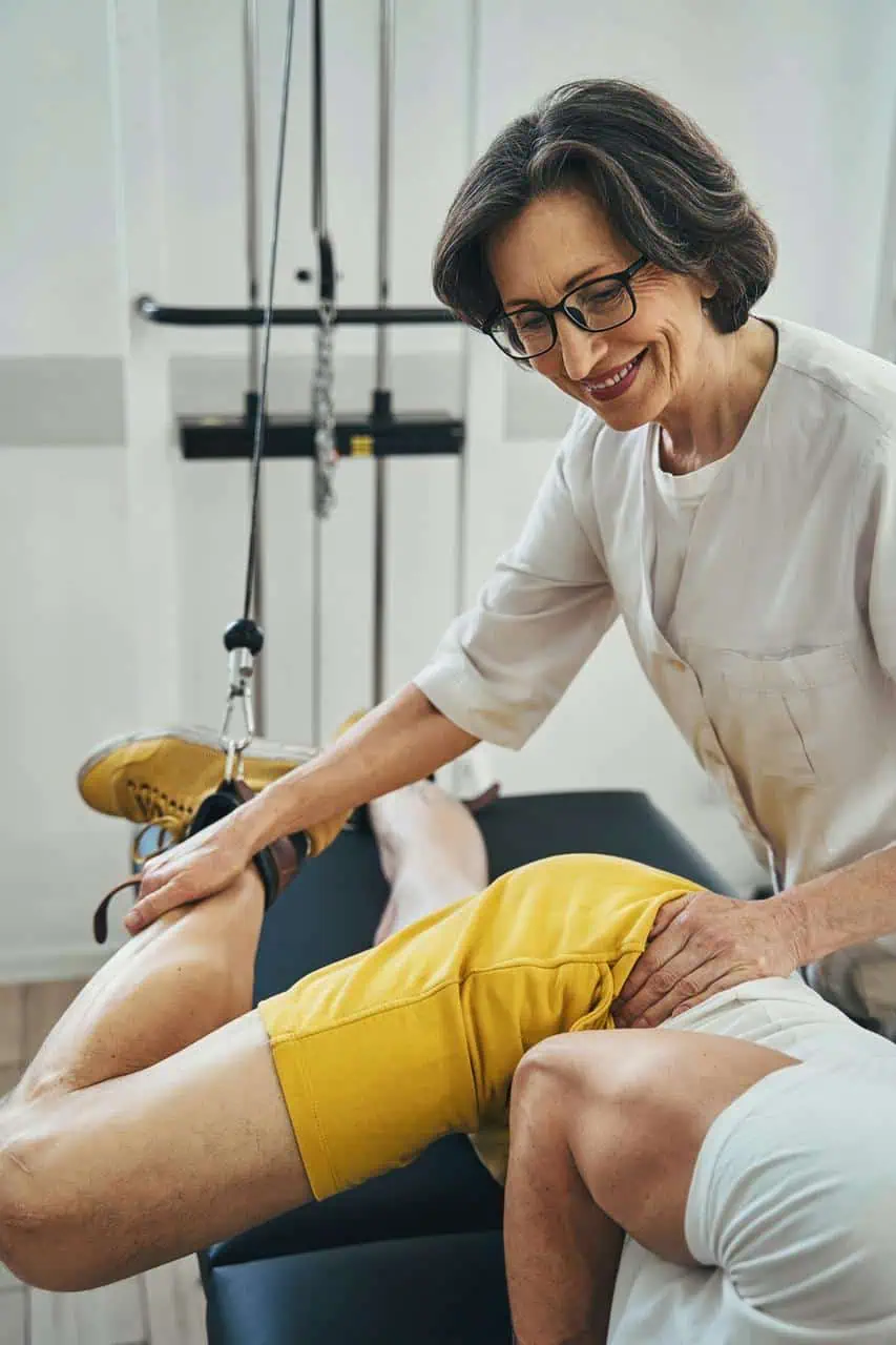 Female physical therapist treating patient leg injury in rehabilitation clinic