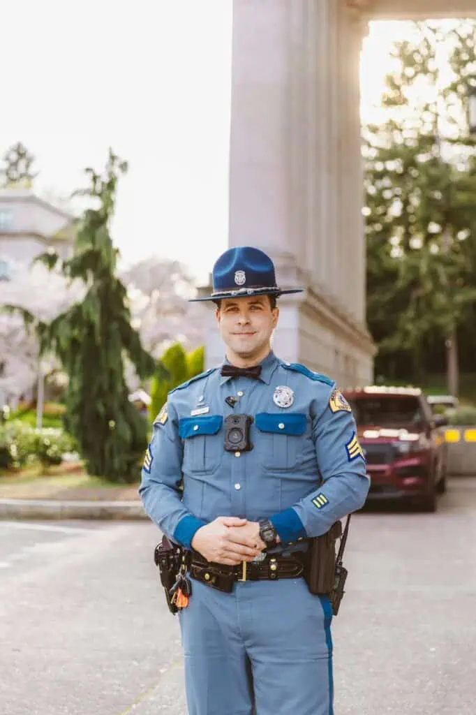 Uniformed police officer standing outdoors with badge and body camera