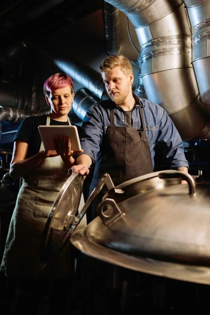 Product testing compliance specialists using tablet to monitor brewery quality control