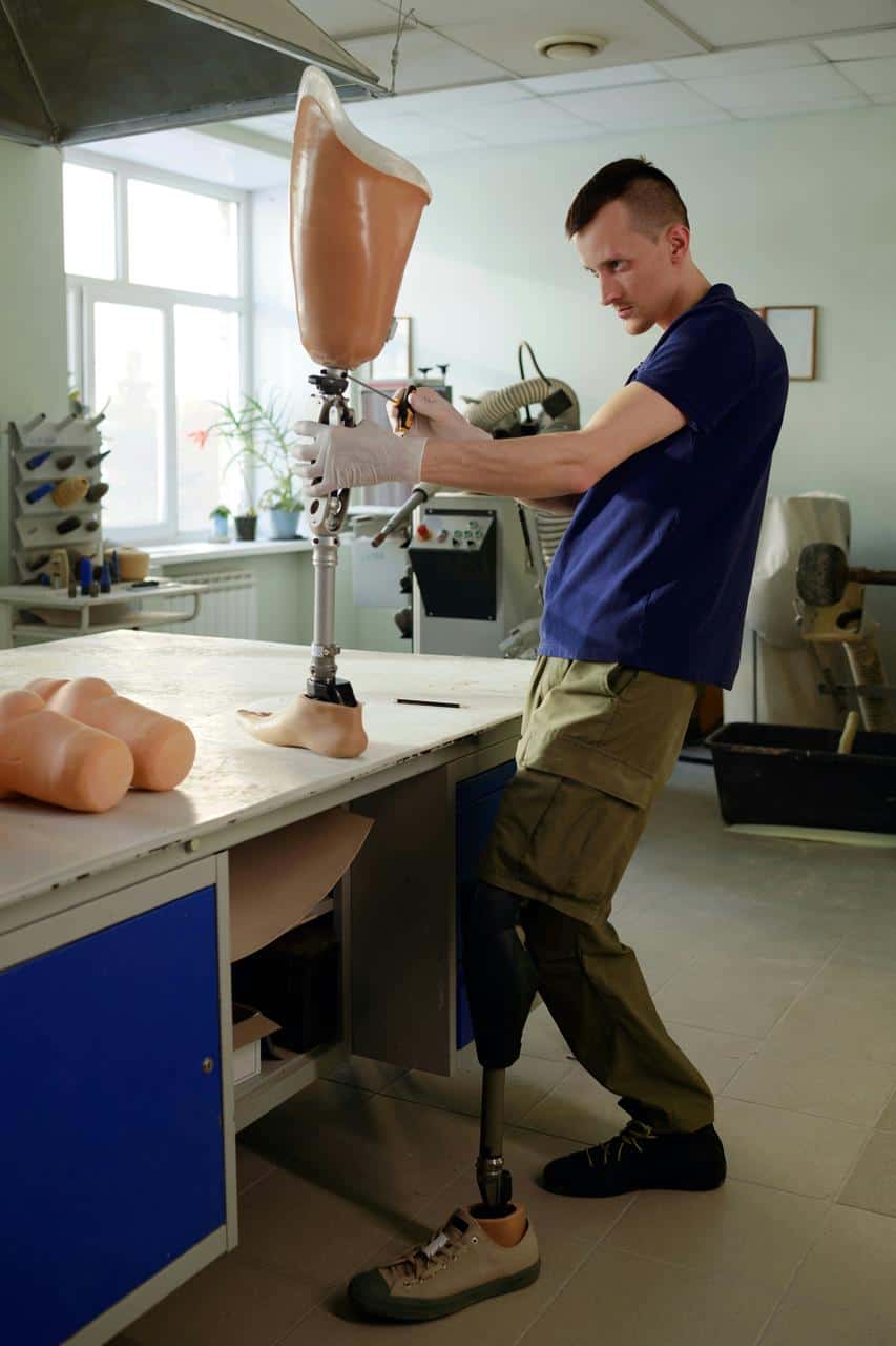 Prosthetics orthotics specialist adjusting prosthetic leg device in clinical workshop
