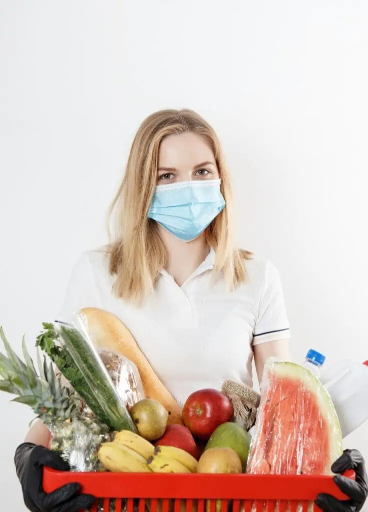 Public health educator wearing mask holding grocery basket with fresh produce