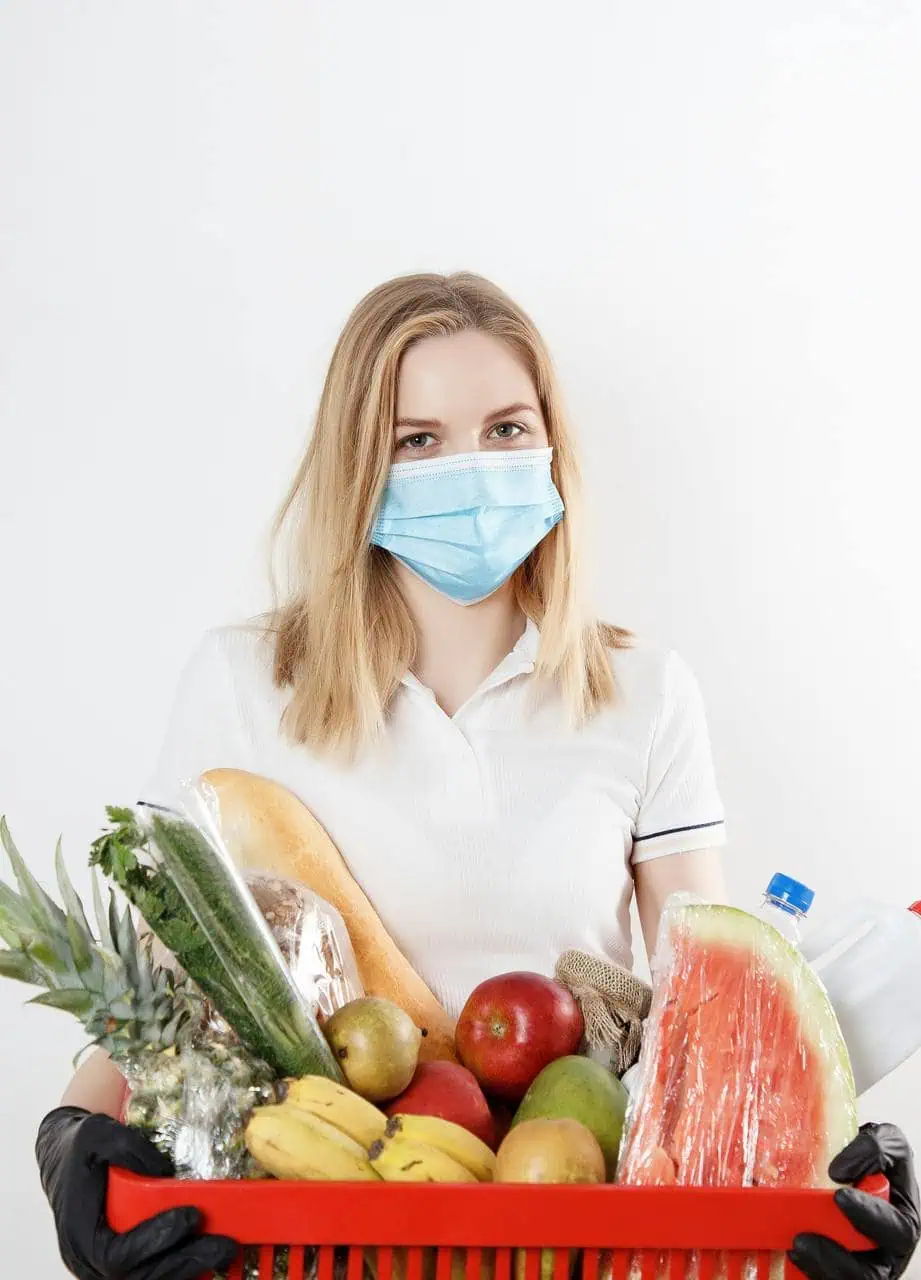 Public health educator wearing mask holding grocery basket with fresh produce