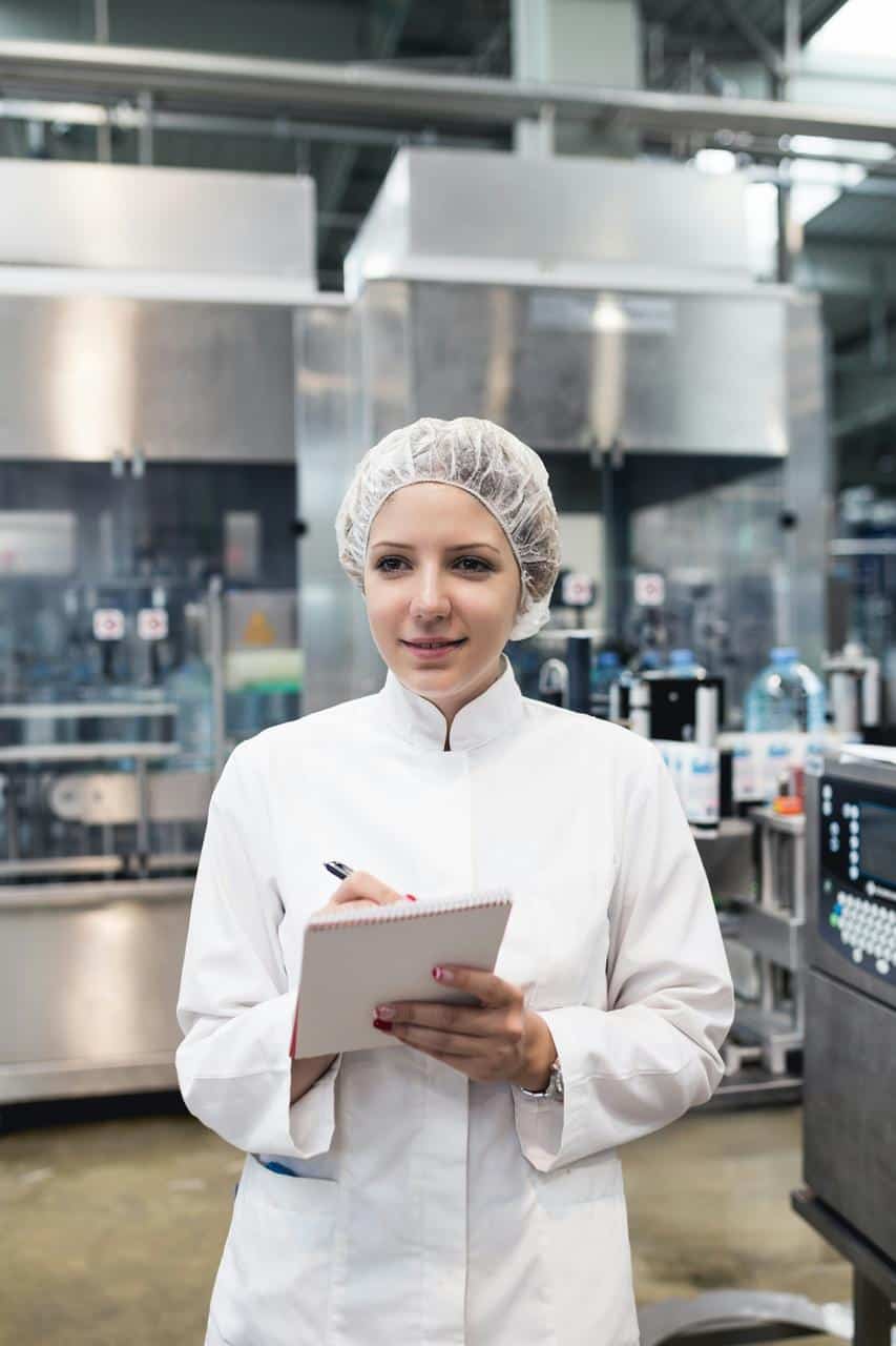 Female quality control inspector with notebook in sterile food processing facility