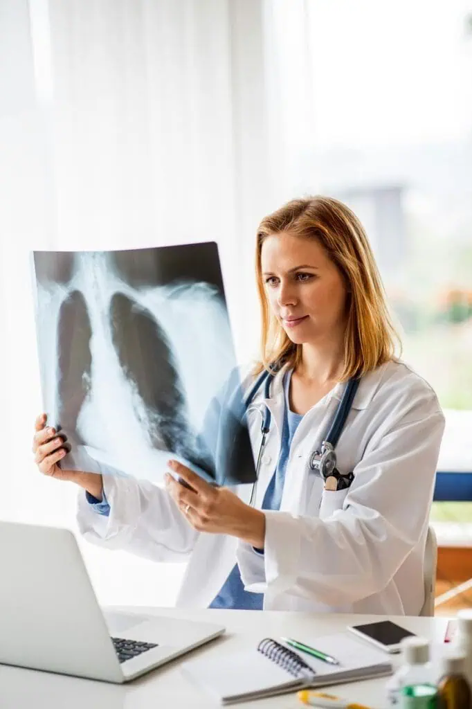  Female radiologist examining chest X-ray with stethoscope in medical office