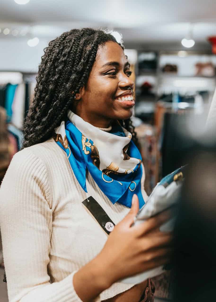 Retail store manager smiling while organizing merchandise in clothing store