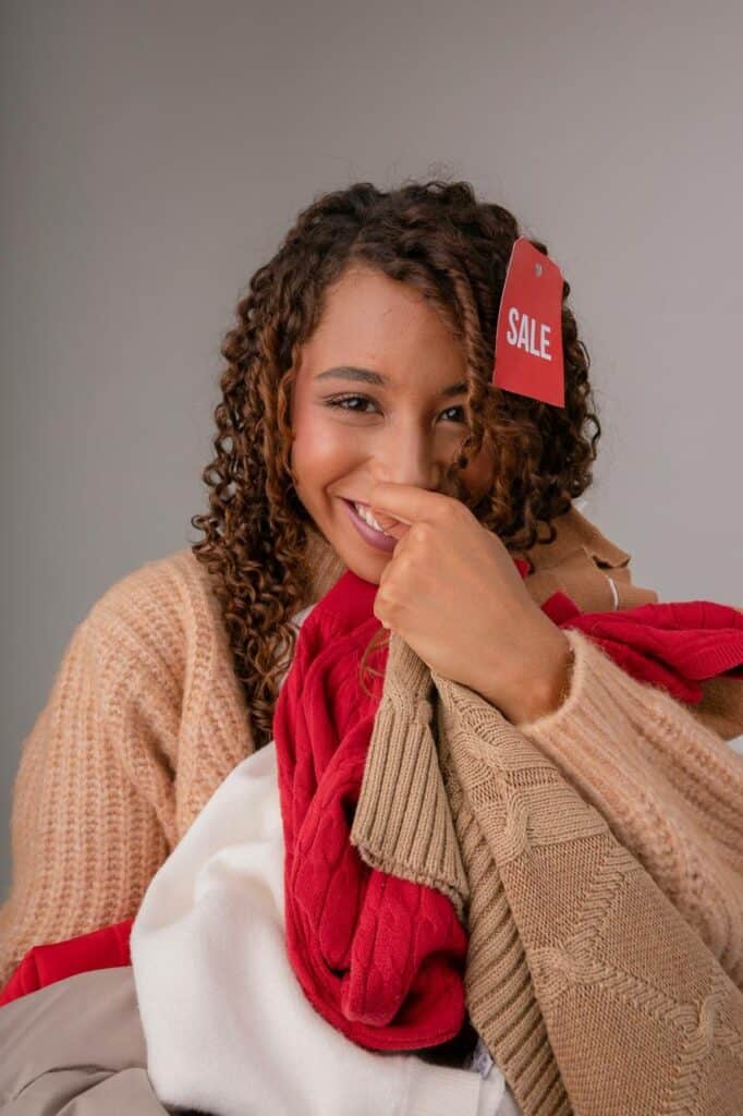 Sales representative holding discounted clothing with smile