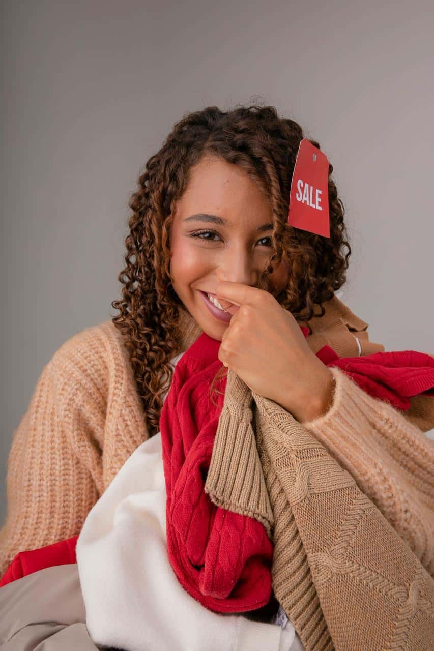 Sales representative holding discounted clothing with smile