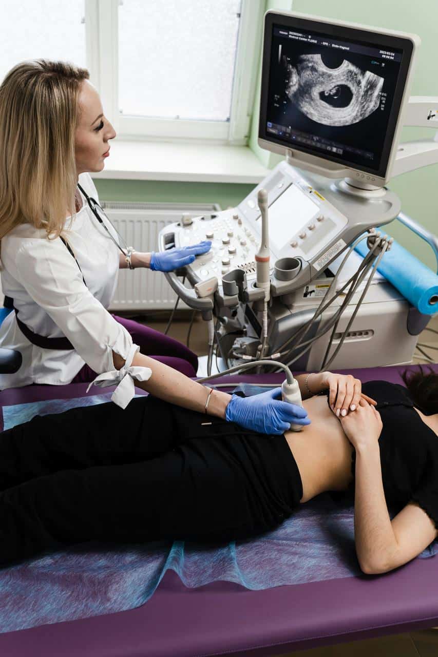 Ultrasound technician performing diagnostic imaging scan with patient on examination table