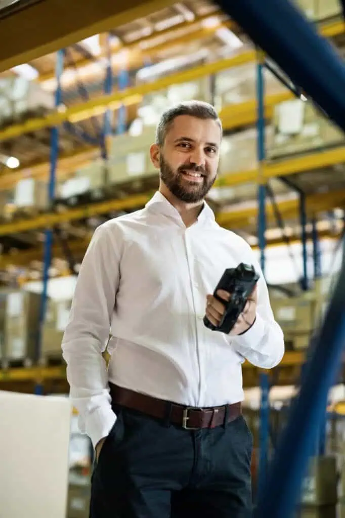 Warehouse fulfillment manager holding scanner in organized logistics facility