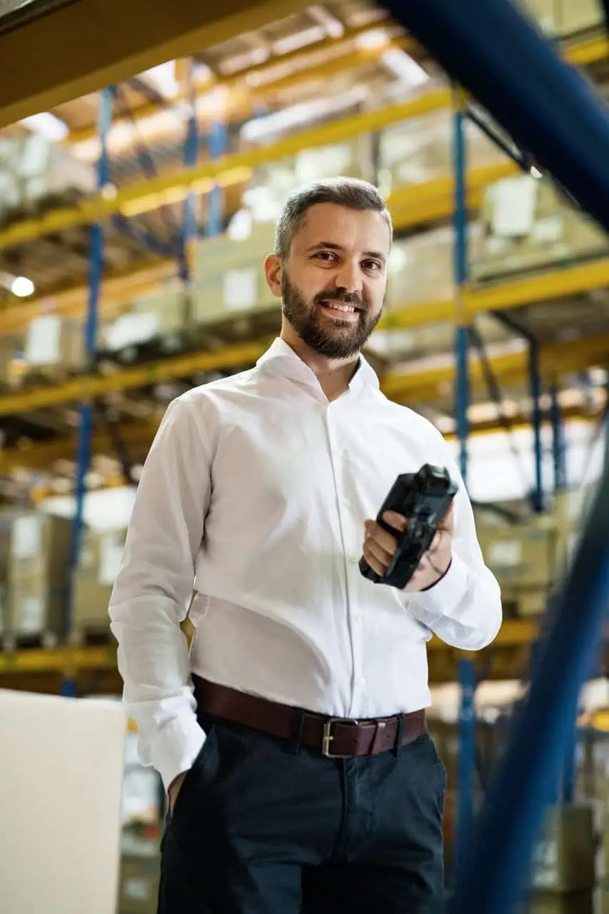 Warehouse fulfillment manager holding scanner in organized logistics facility