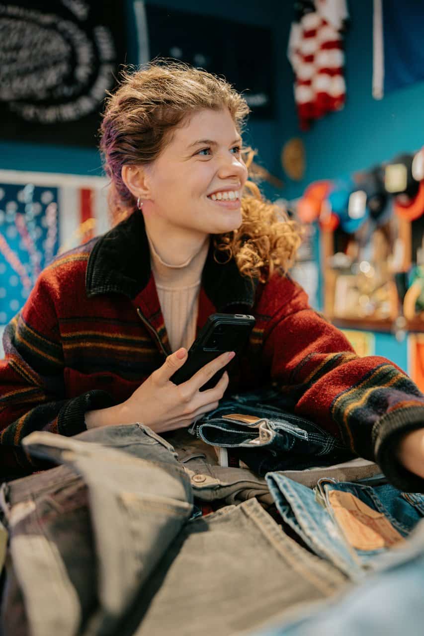 Wholesale buyer examining denim inventory with mobile device in vibrant retail setting