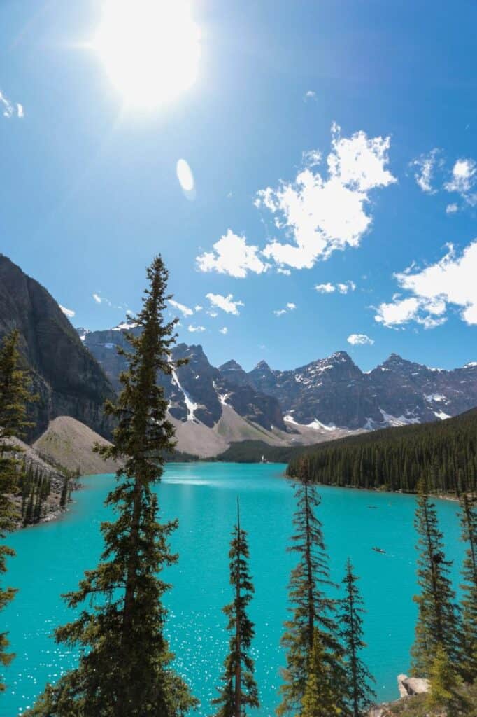 Turquoise river flowing through a dense forest with towering mountains in the background, symbolizing adventure, education, and career opportunities in Canada.